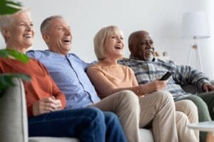 group of seniors sitting on a couch watching tv together