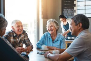 a group of senior friends sitting at a table chatting at a local coffee shop
